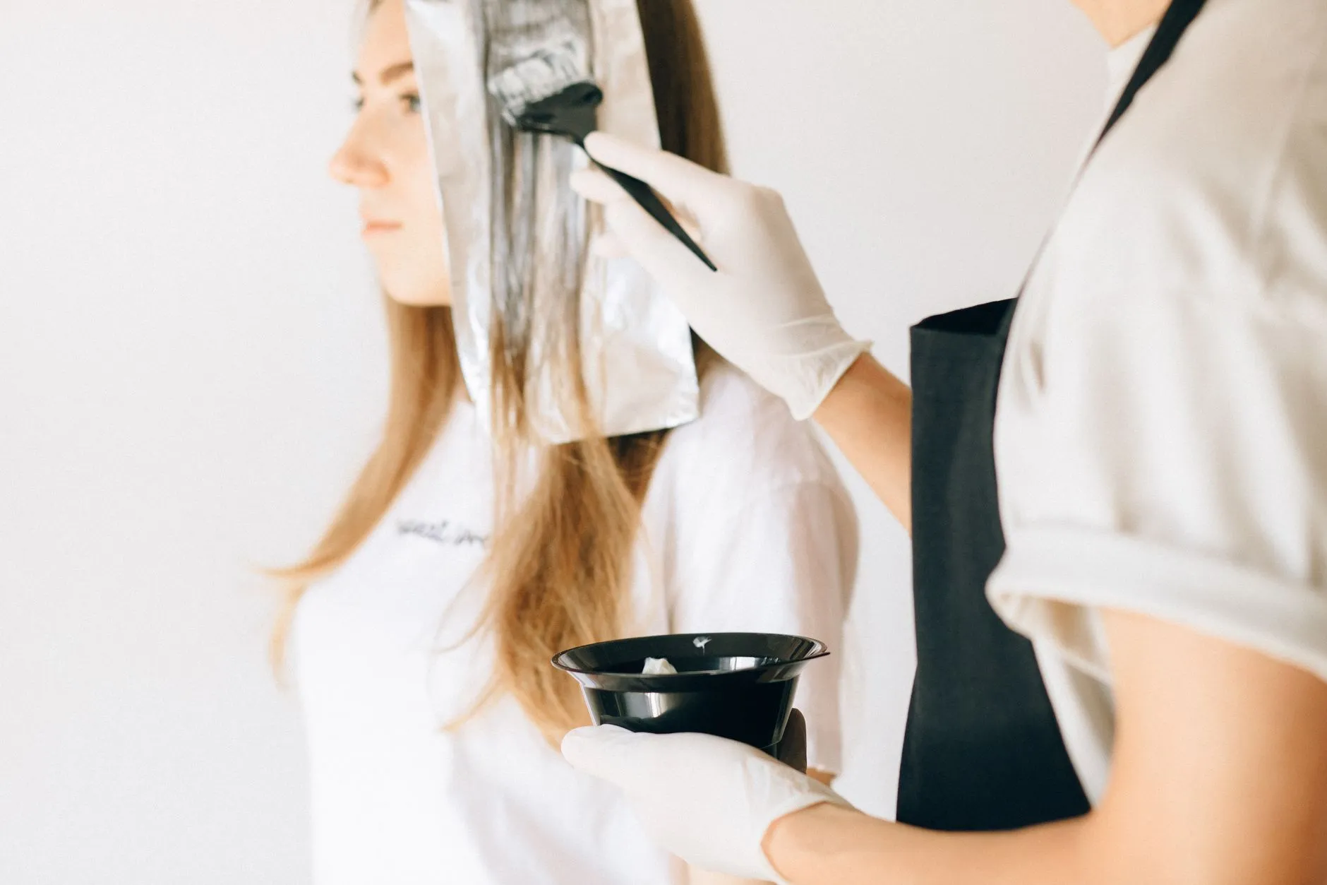A stylist painting colour onto long blonde hair with a tint brush