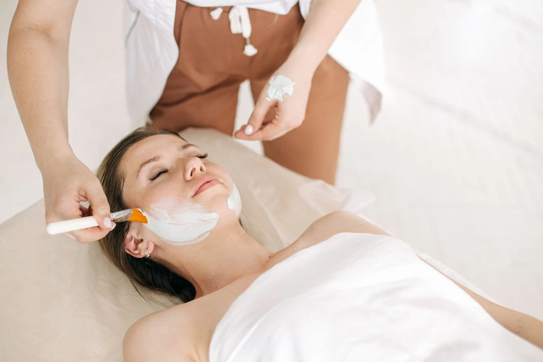 A therapist applying a facial mask with a brush