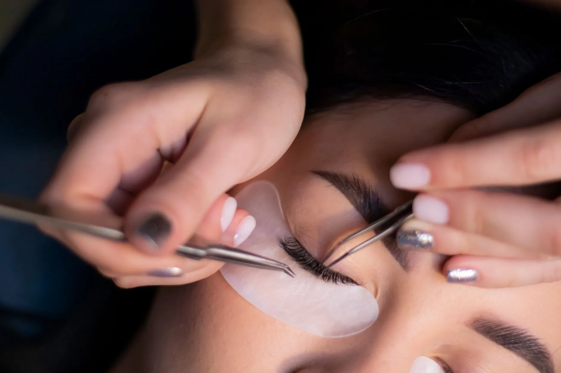 Individual lash extensions being applied with tweezers
