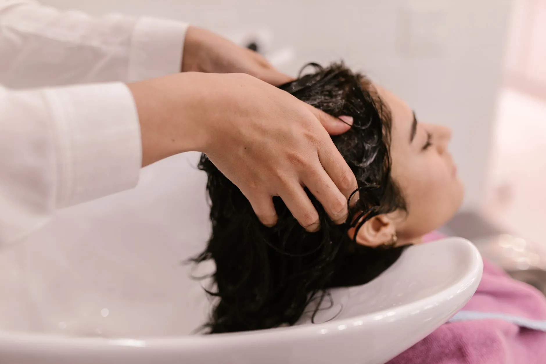 Hands massaging a client's scalp at the backwash basin
