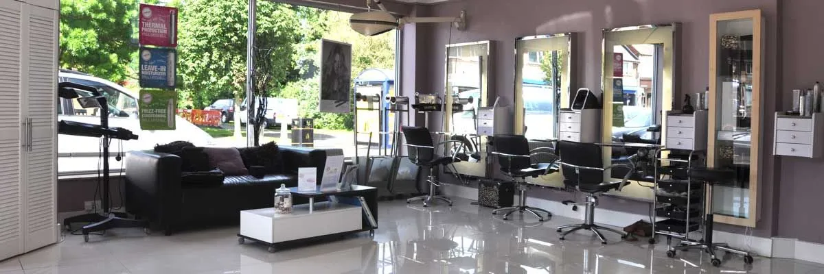 Inside the salon: white floor, mauve walls and a row of styling stations at the window